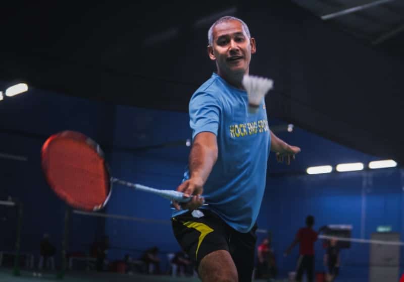 Man playing Badminton which is a game similar to tennis.