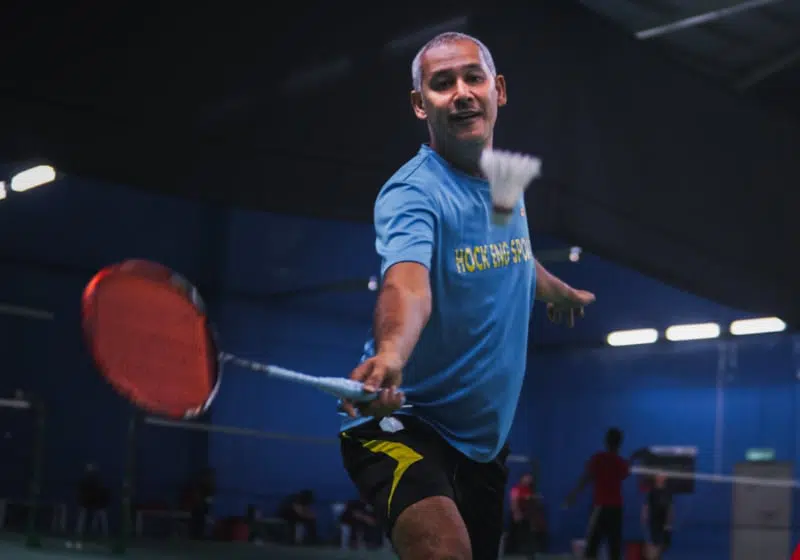 Man playing Badminton which is a game similar to tennis.