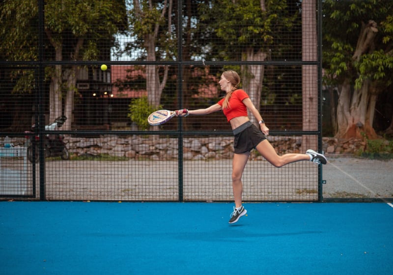 Padel tennis is similar to tennis. Girl playing padel tennis outdoors.
